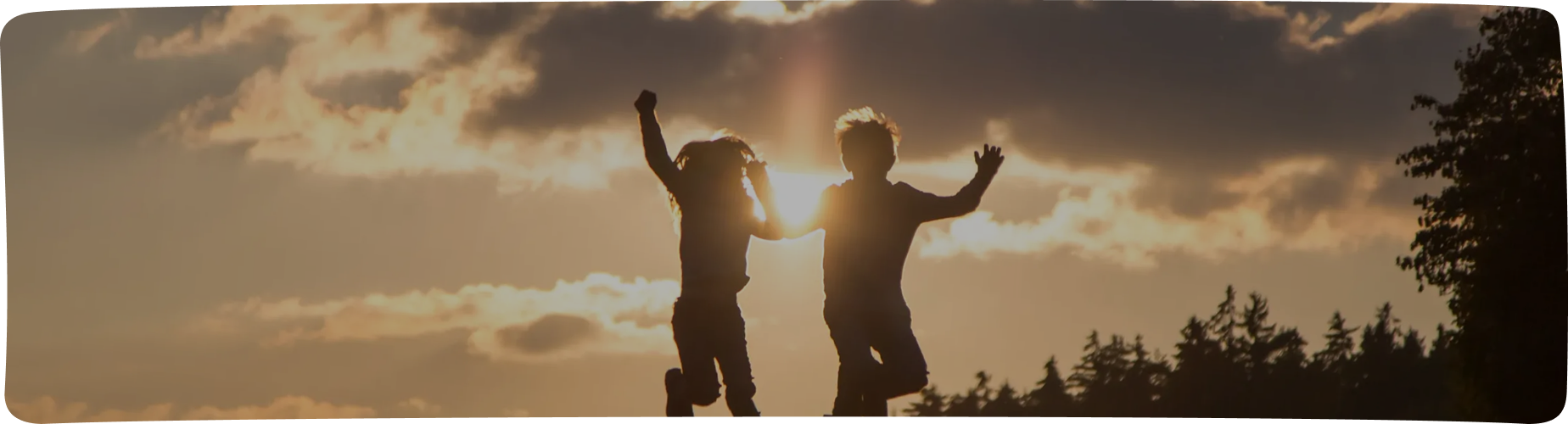 Children leaping in a field at sunset
